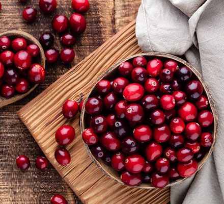 Ripe cranberry in wooden bowl on wooden table.